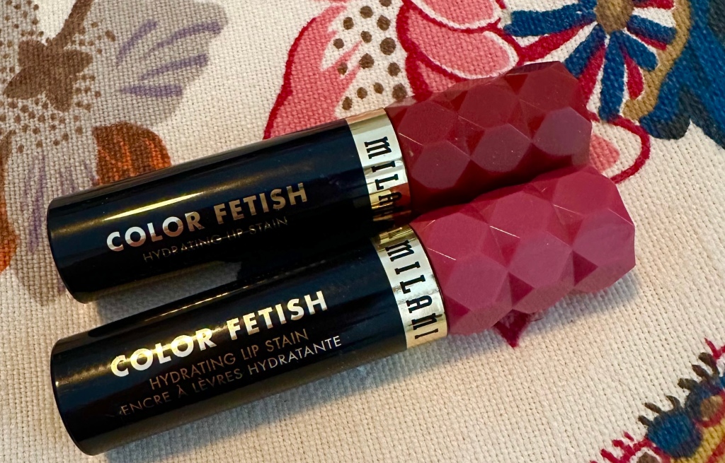 Milani Color Fetish Hydrating Lip Oils. shown in the shades Mahogany Mami and Rose Rising on bottom. 