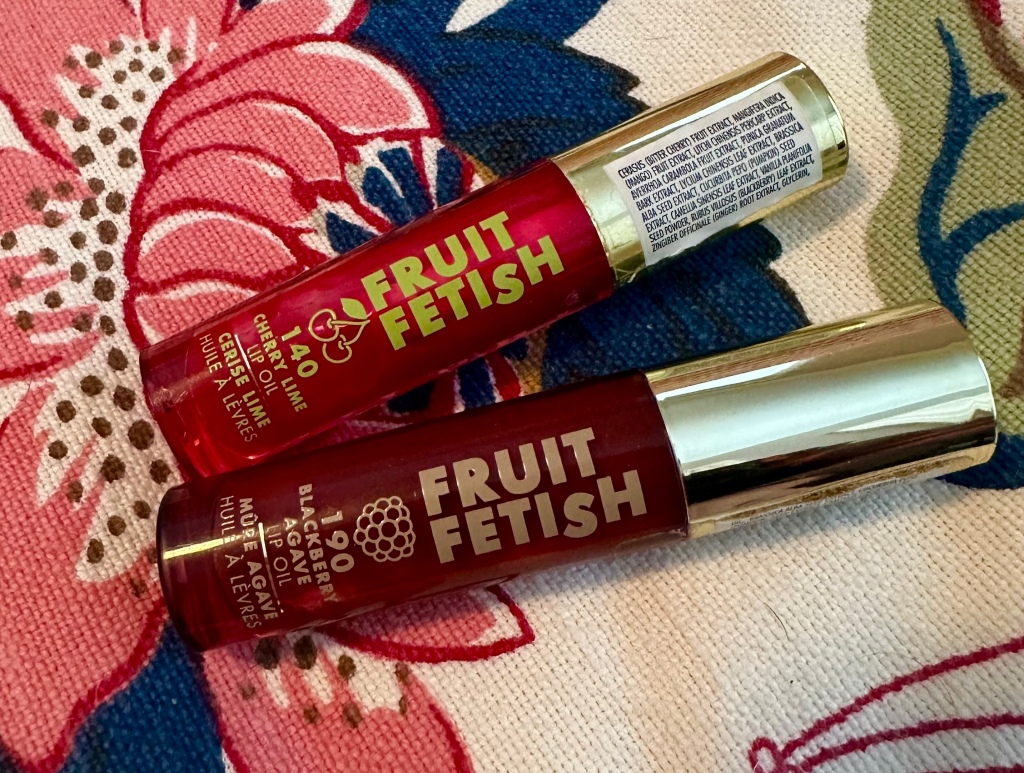 Milani Fruit Fetish Lip Oils, shown in the shades Cherry Lime (on top) and Blackberry Agave (bottom). 